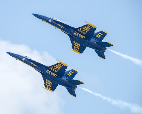Free Two US Navy Blue Angels fighter jets performing an aerobatic maneuver in blue sky. Stock Photo