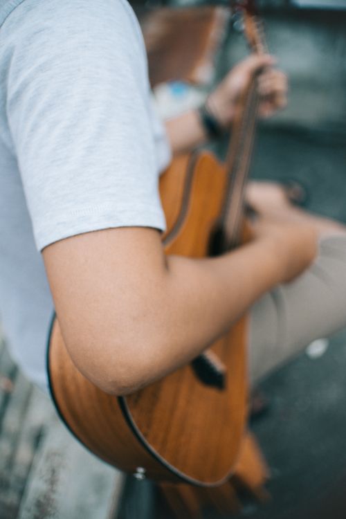 Free Close-up of a man playing an acoustic guitar outside, capturing the essence of music and leisure. Stock Photo