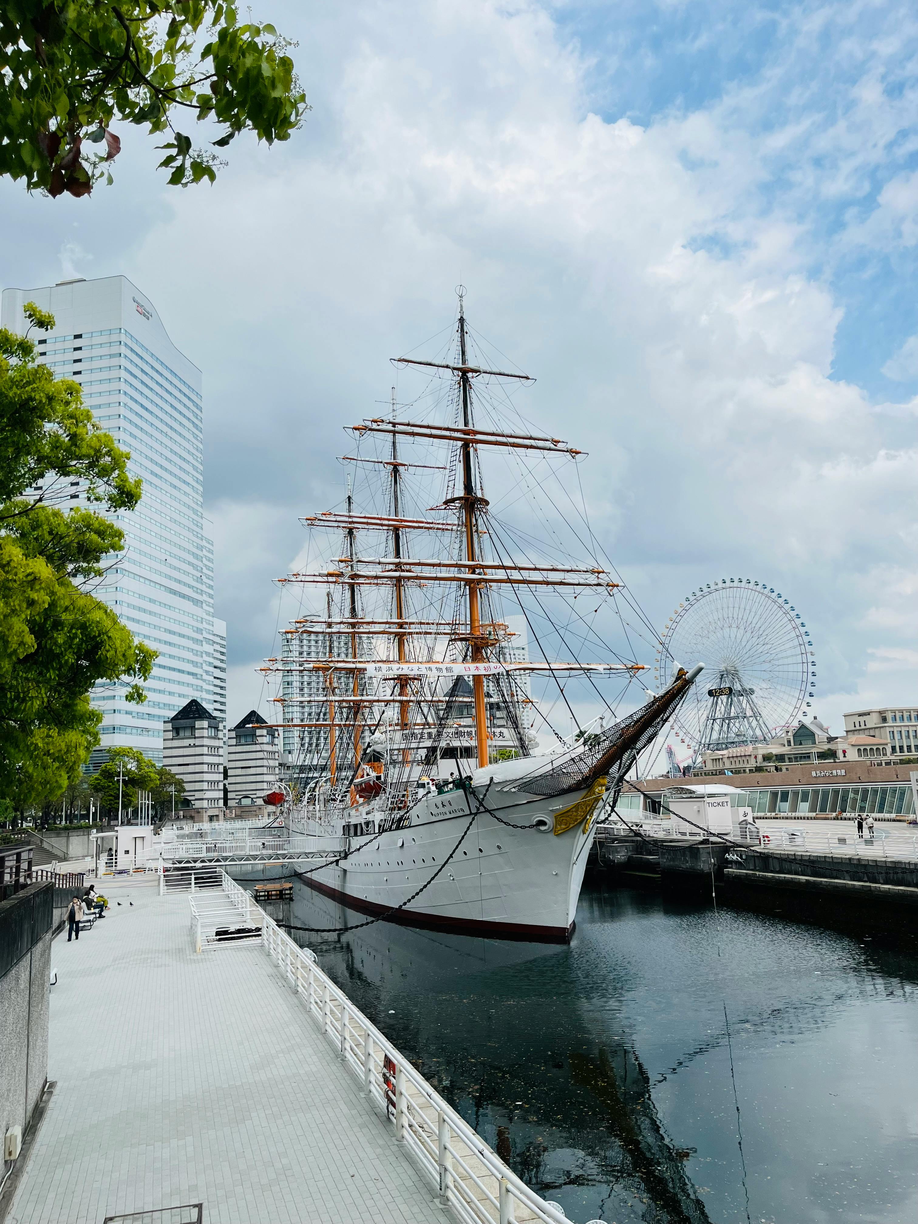 The historic Nippon Maru ship docked at Yokohama harbor under a bright sky, showcasing the city's skyline.