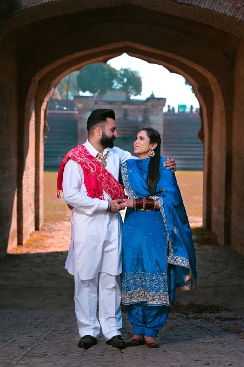 Free A joyful Indian couple in traditional attire standing in an archway, Amritsar, India. Stock Photo