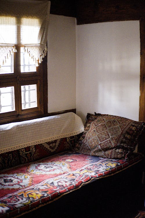 A Bed with a Blanket with a Traditional Pattern by the Window in a House 