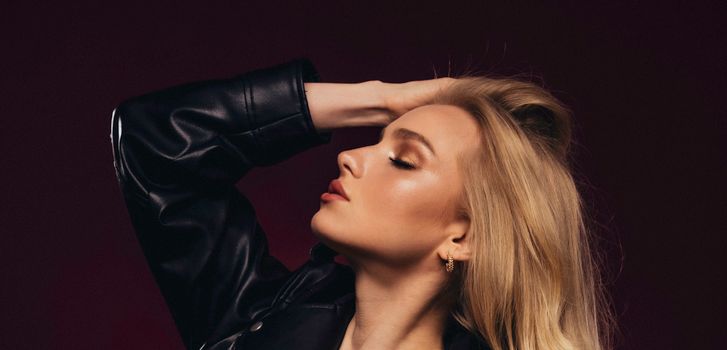 A beautiful young blonde woman poses gracefully with eyes closed, exuding elegance and style.