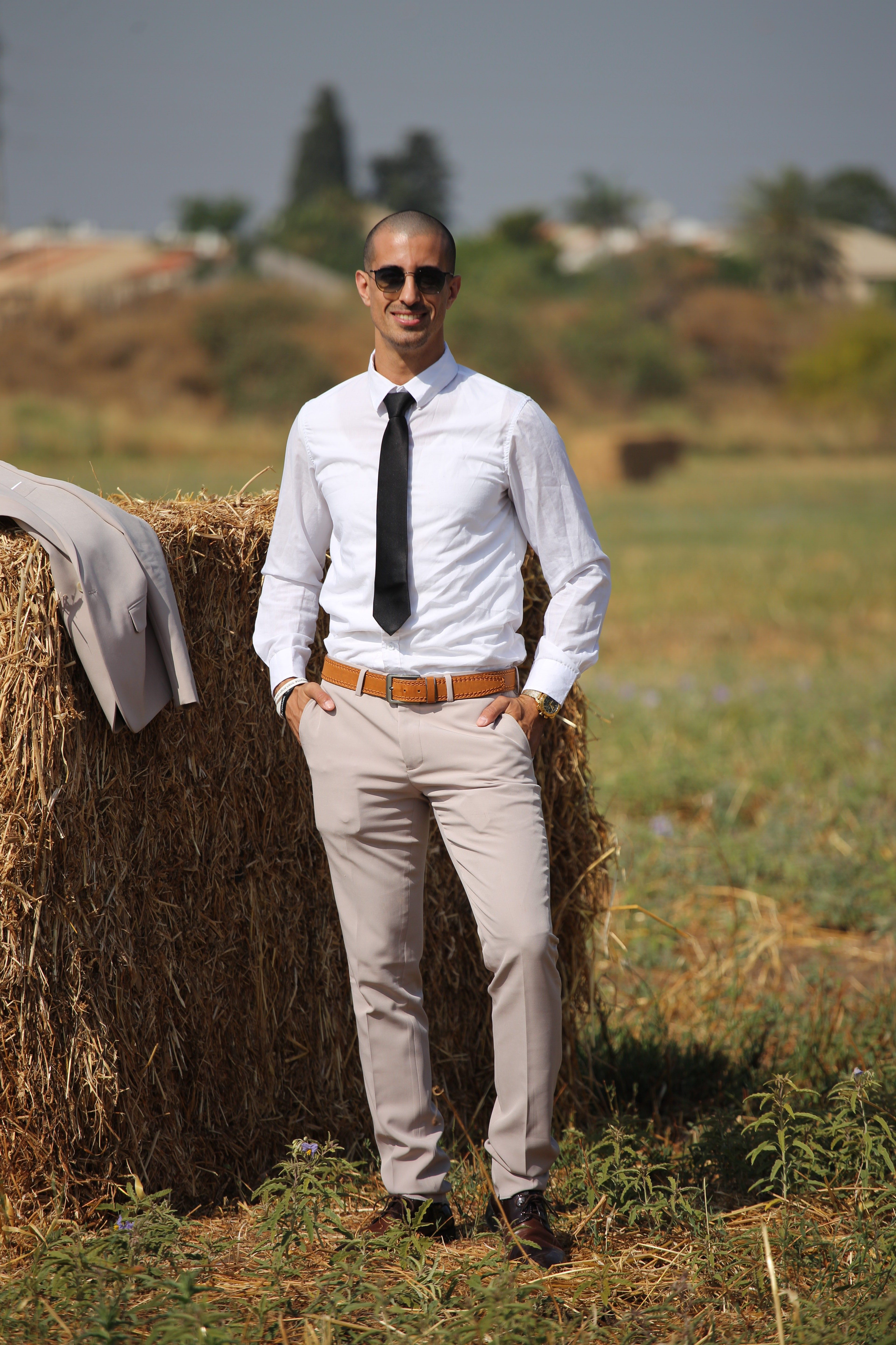 Professional man in suit enjoying a sunny day outdoors by a haystack in a field.