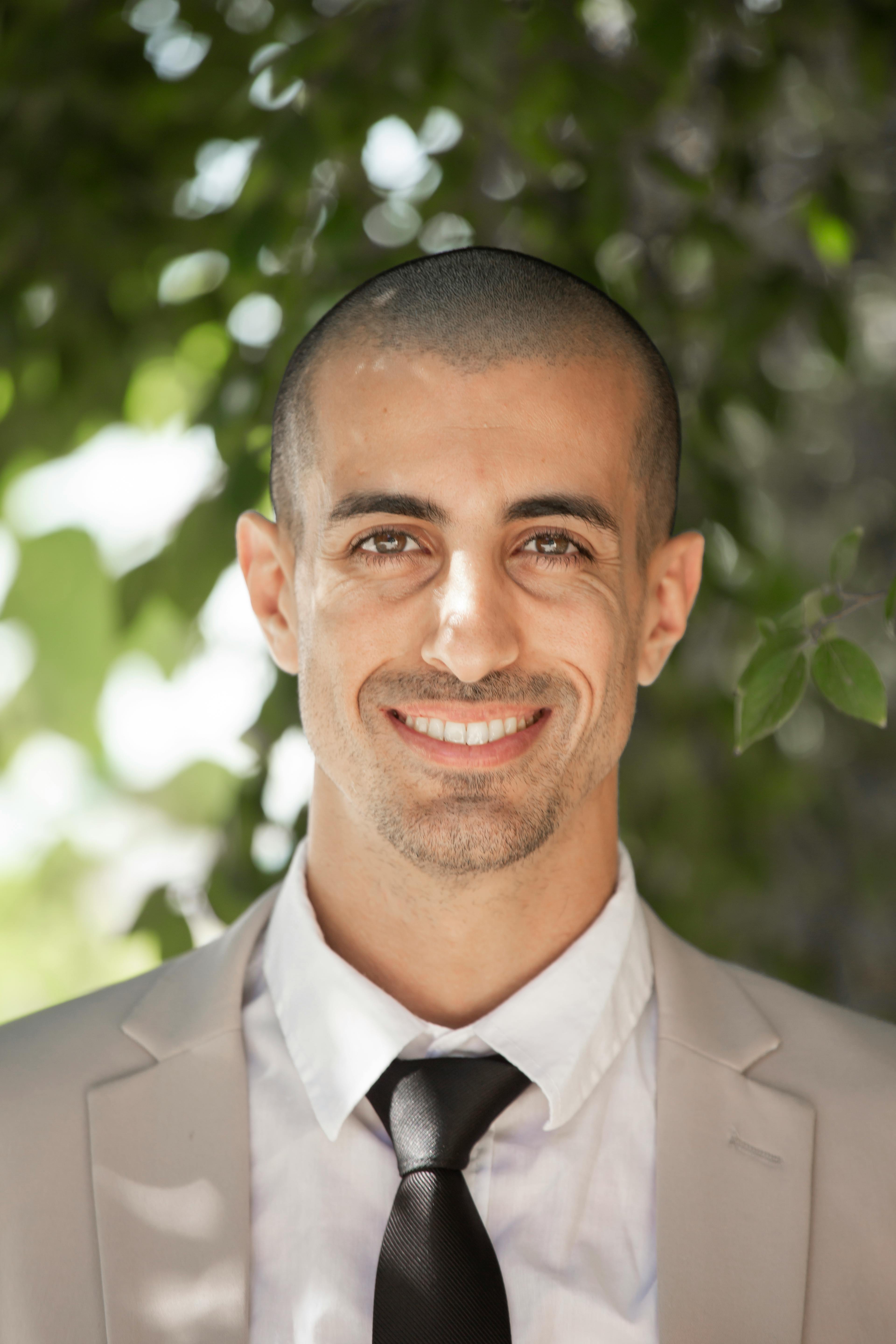 Portrait of a smiling business professional outdoors with greenery background.
