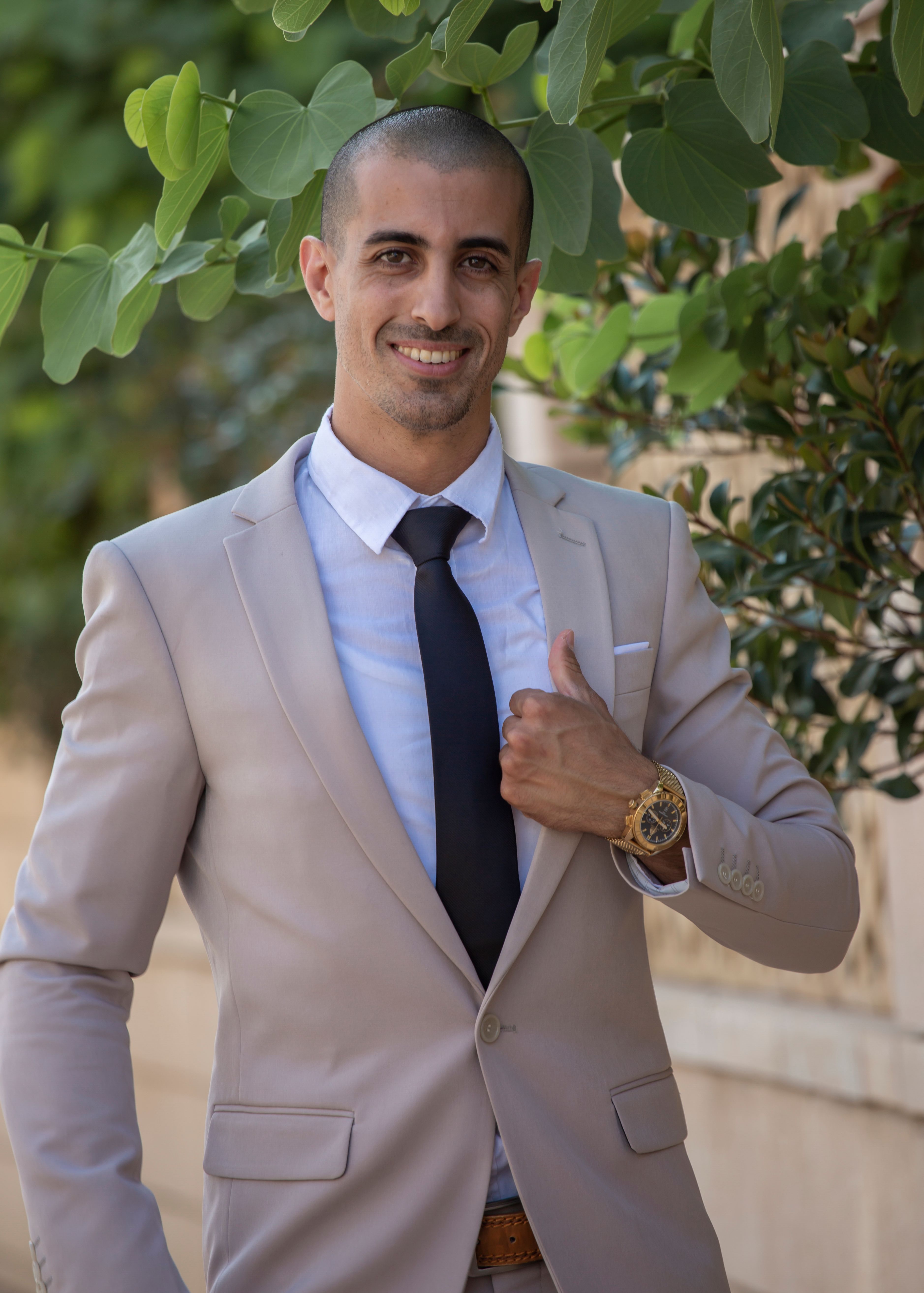 A confident businessman poses outdoors in a stylish beige suit, exuding professionalism and success.