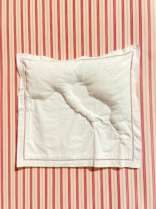 A White Pillow Lying on a Red Striped Background 