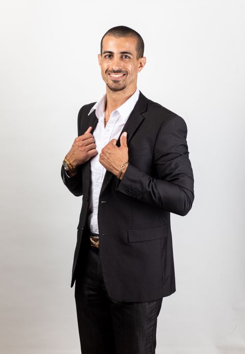 Free Well-dressed man confidently posing in a black suit with a white background. Stock Photo