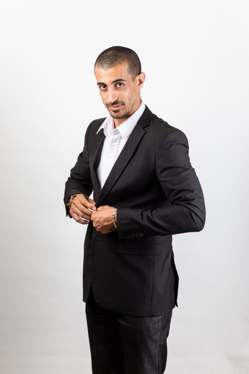 Free Well-dressed man in a black suit posing confidently in a studio with a white background. Stock Photo