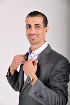 Confident businessman in a gray suit smiling with a white background, perfect for corporate themes.