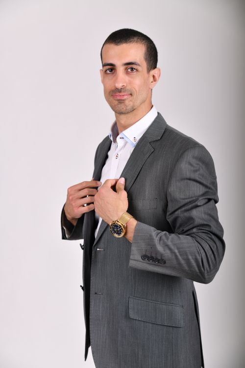 Free Elegant man in a suit posing confidently against a white background, captured in a studio setting. Stock Photo