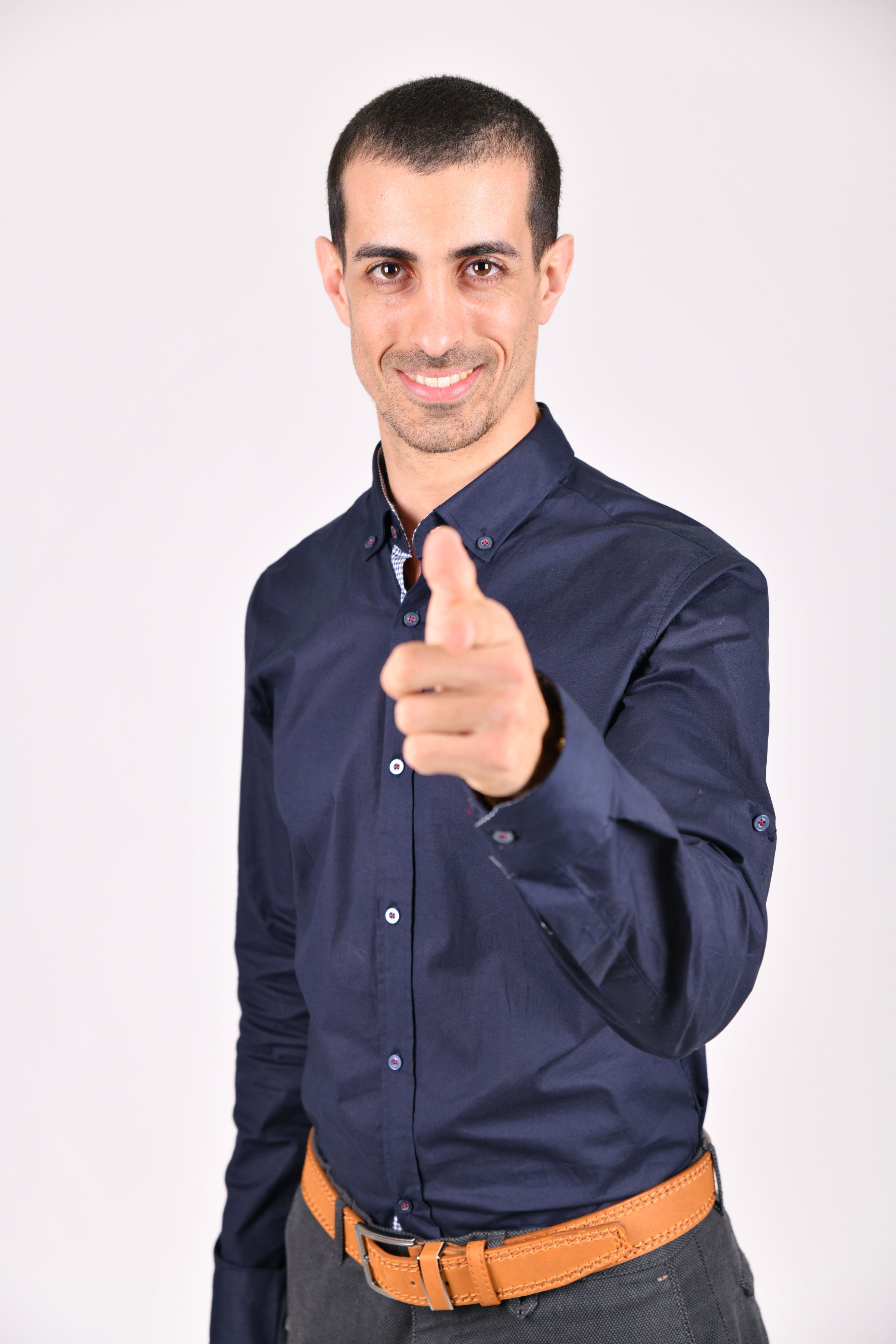 A confident businessman in a blue shirt pointing forward with a smile.