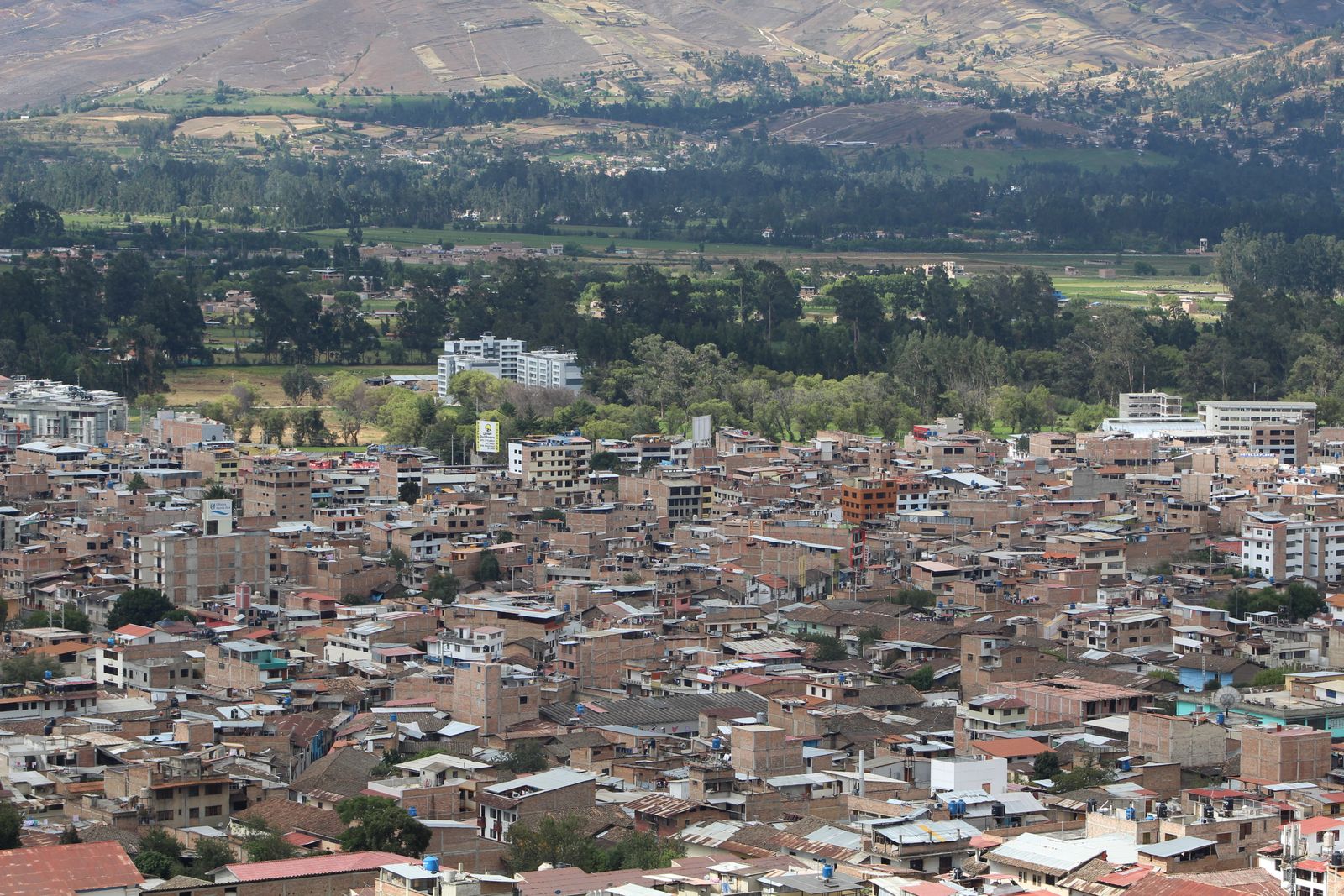 Vista aérea de la ciudad de Cajamarca, con casas de techos rojizos y el valle verde al fondo