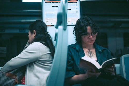 Woman Sitting and Reading Book in Public Transport