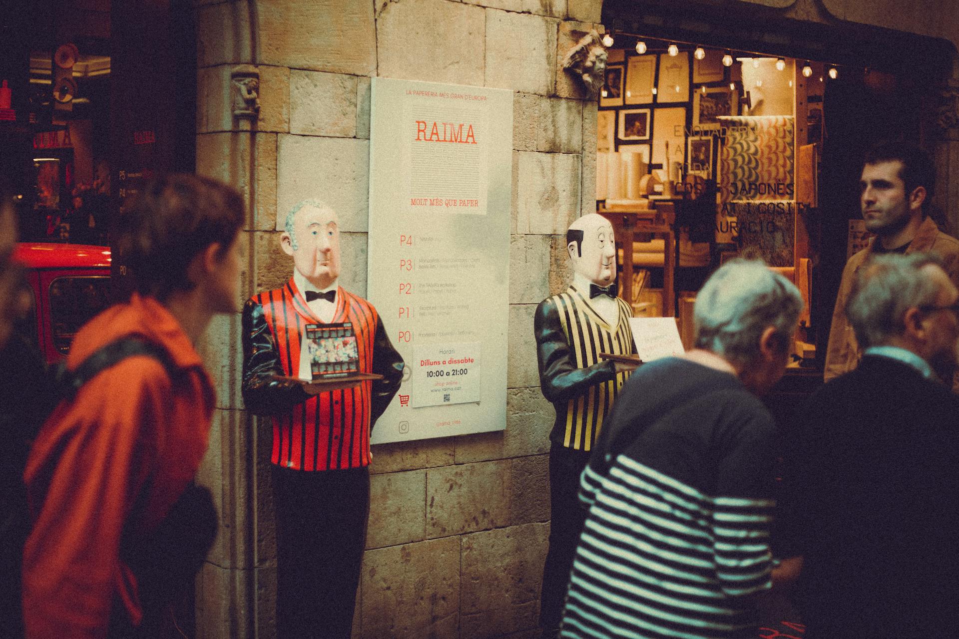 Charming street scene featuring mannequin butlers and passersby outside an illuminated vintage shop.