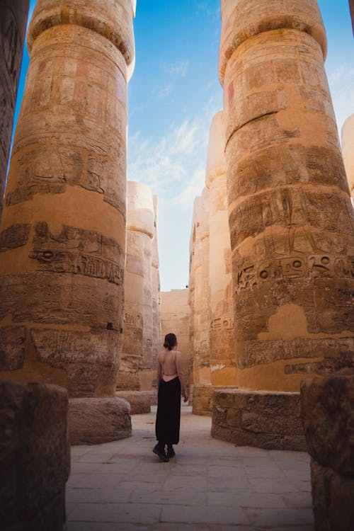 A Woman Standing between Columns at the Karnak Temple Complex in Luxor, Egypt