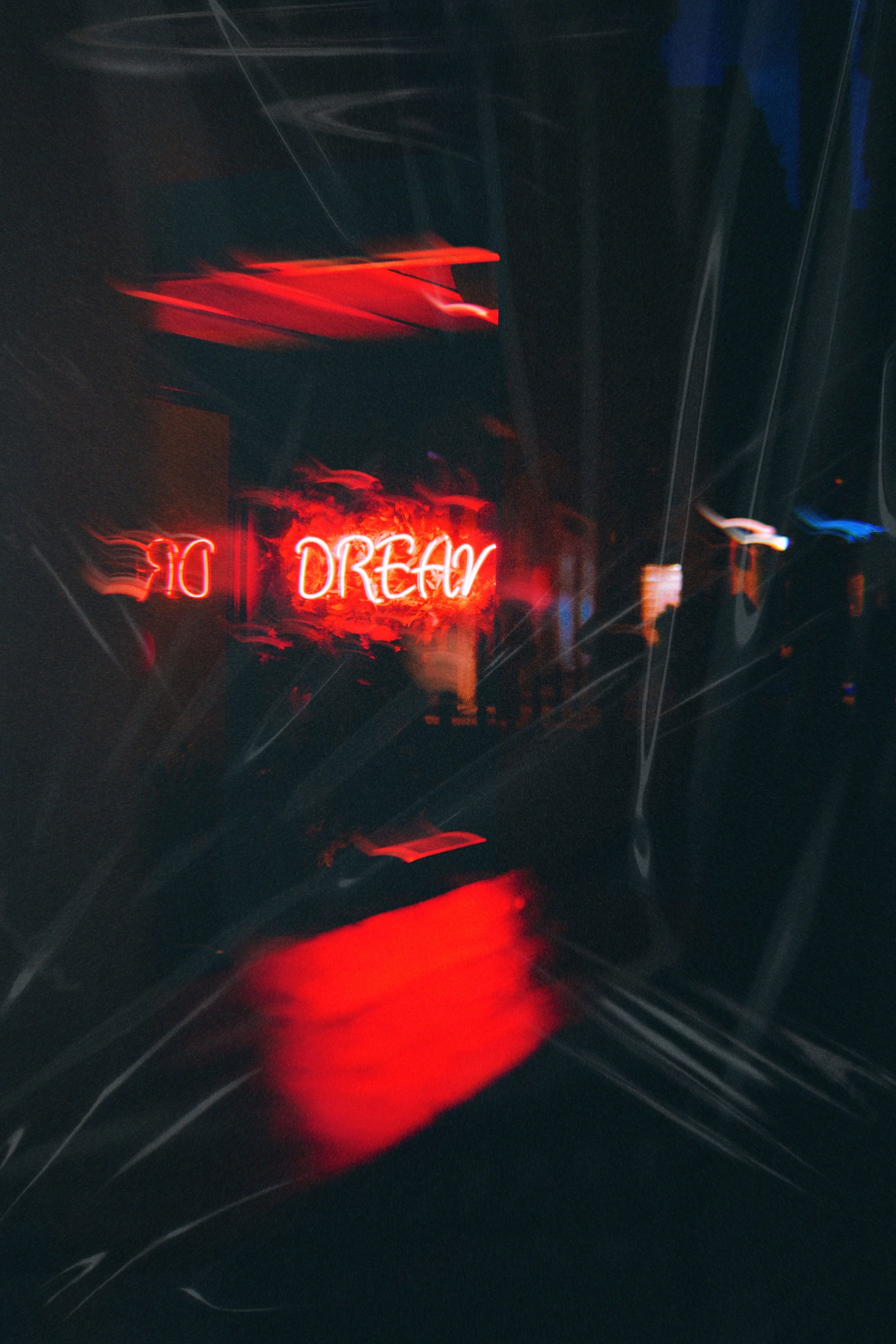 Artistic concept of neon sign reading 'DREAM' in a blurred setting with dark ambiance.
