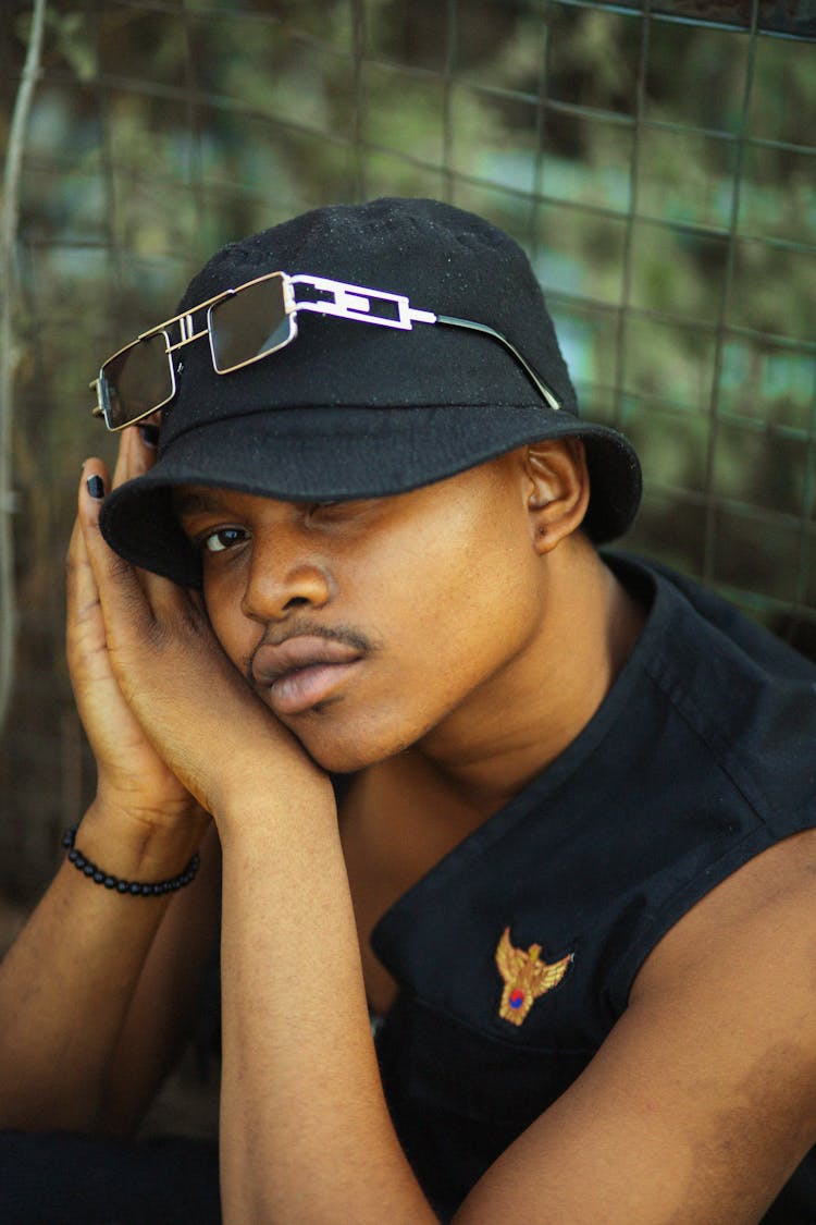 Young Man In A Bucket Hat And Vest Sitting Outside 