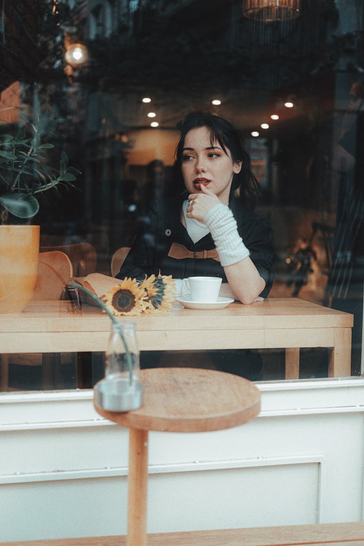 Young Woman Sitting In A Cafe Photographed From Behind A Window 