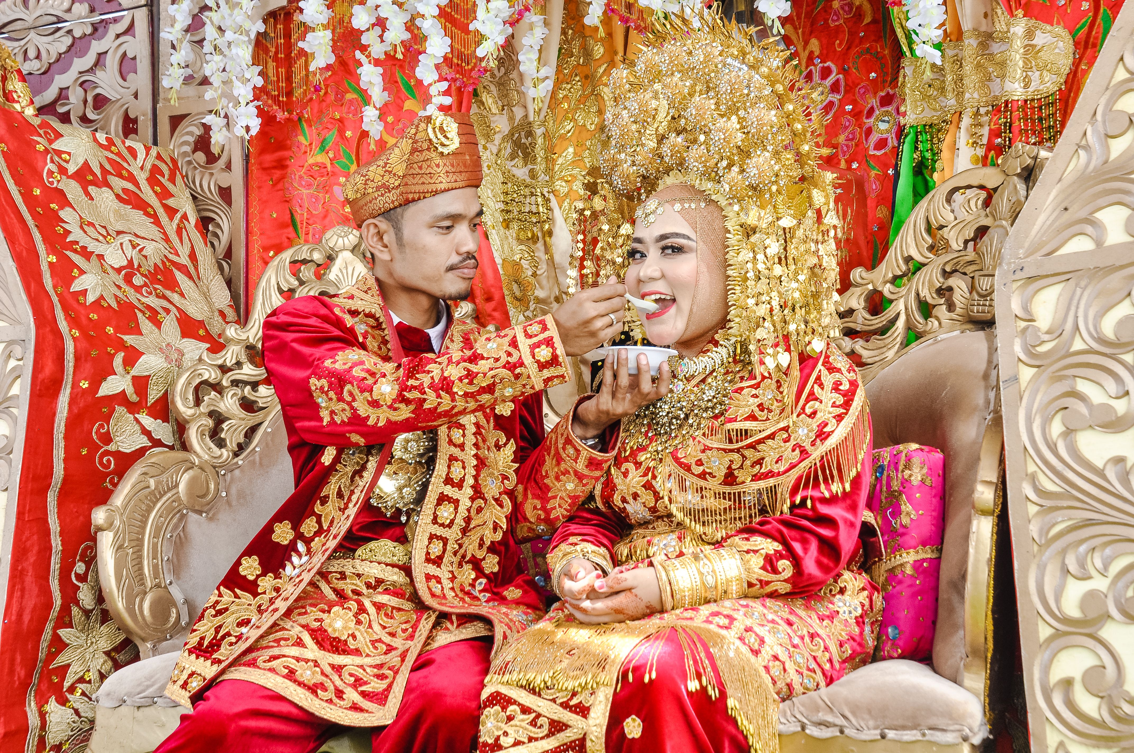 Bride and groom in elaborate traditional attire during a cultural wedding ceremony.