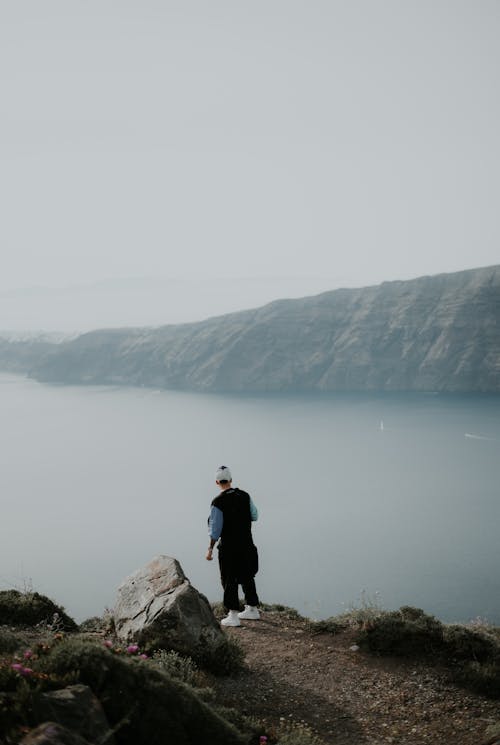 Man Standing on a Hill and Looking at a View of Lake and Mountains 