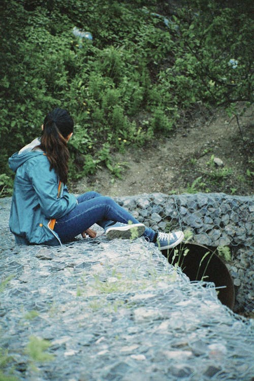Young Woman Sitting on the River Bank and Looking at a View 