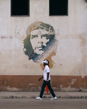 A man walks past a Che Guevara mural on a city street, symbolizing urban life and rebellion.