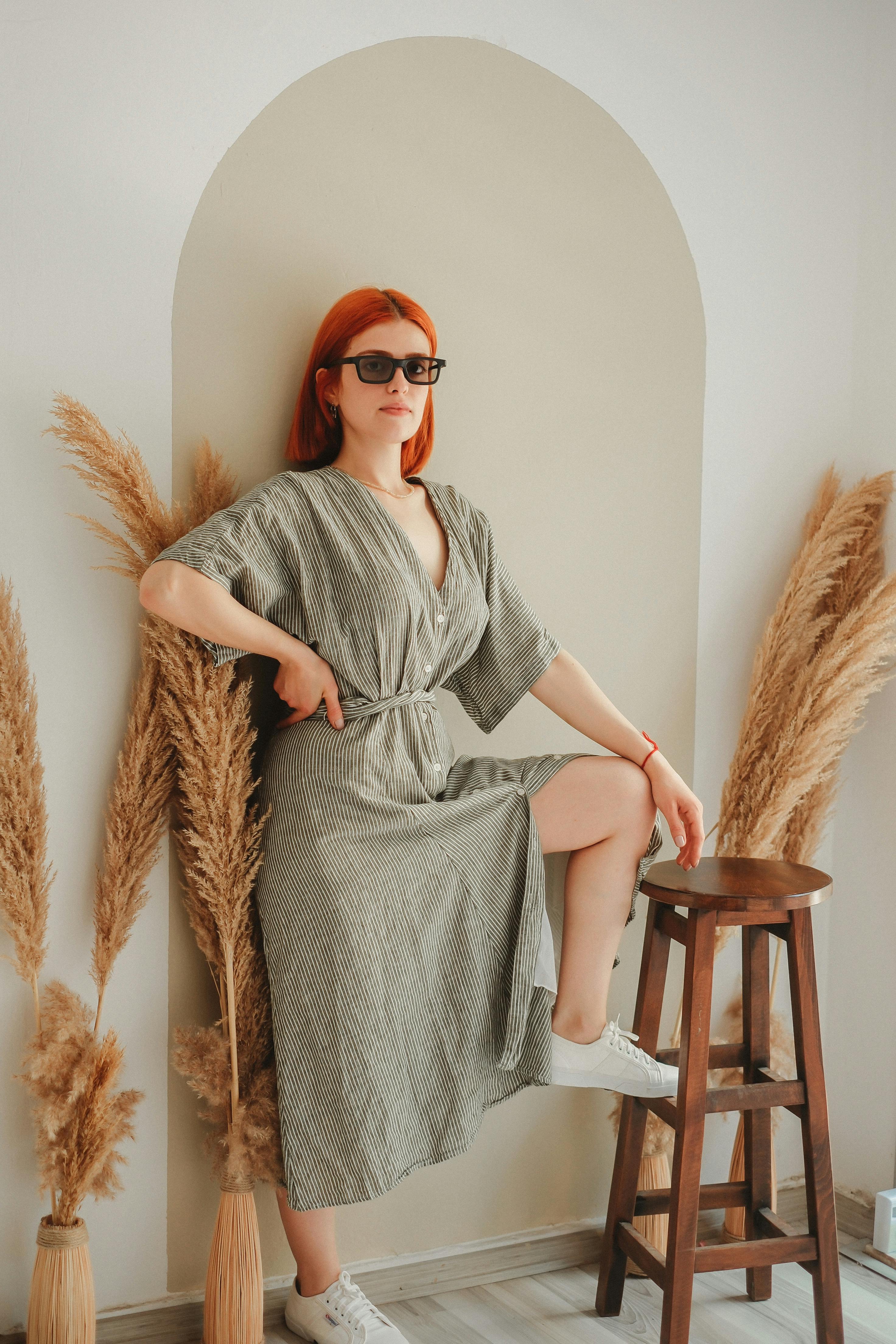 Redhead woman in striped dress posing indoors with a modern, minimalist fashion style.