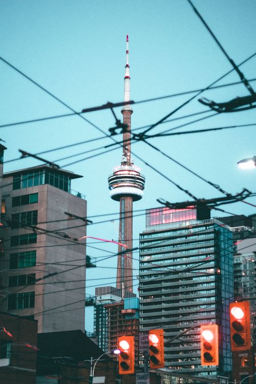 Free Iconic view of Toronto's CN Tower surrounded by urban architecture and traffic lights. Stock Photo