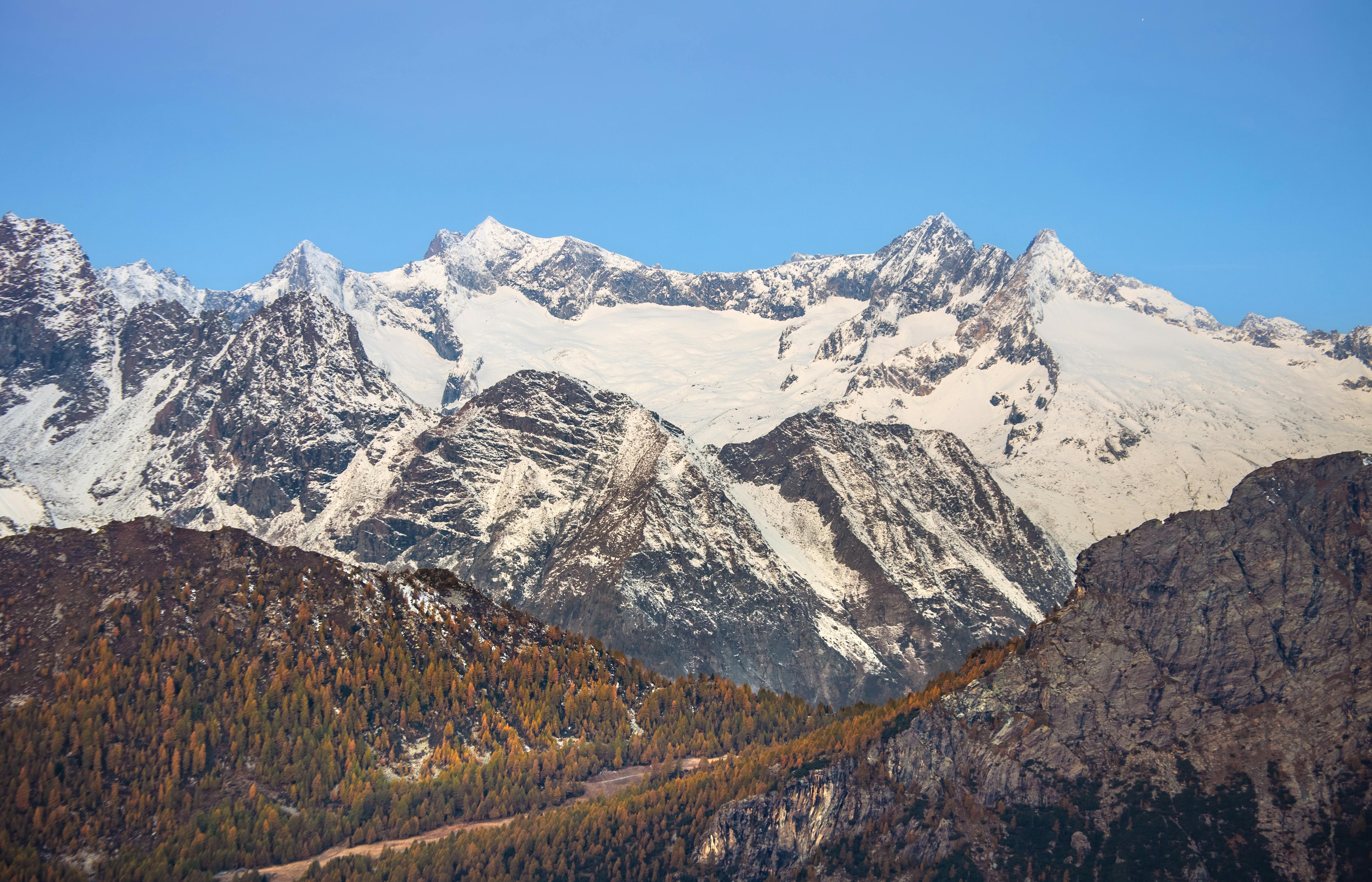 Prescription Goggle Inserts - Stunning view of snow-capped mountains surrounded by autumn forest in the Alps, perfect for nature and travel imagery.