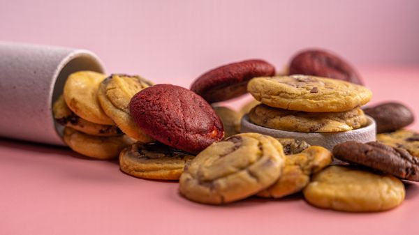 Assorted cookies laid out on a warm pink surface — photo by Ali Dashti on Pexels