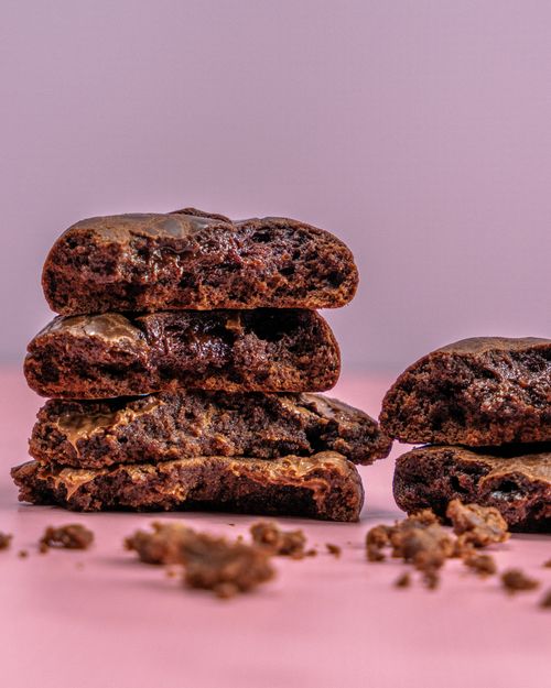 Free Close-up of rich chocolate cookies stacked with crumbs on a pink background Stock Photo