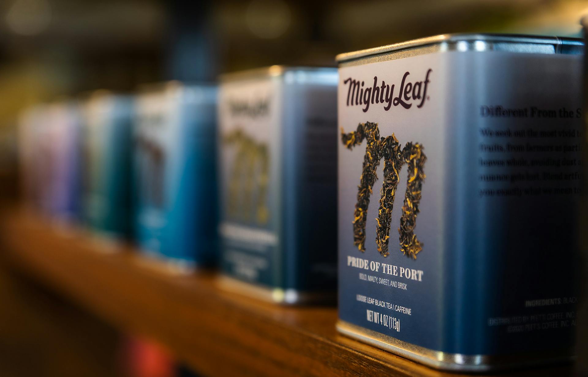 Elegant metal tea containers displayed on a store shelf with focused branding.