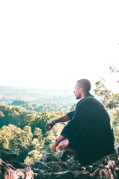 Man Sitting On Cliff Overlooking Trees