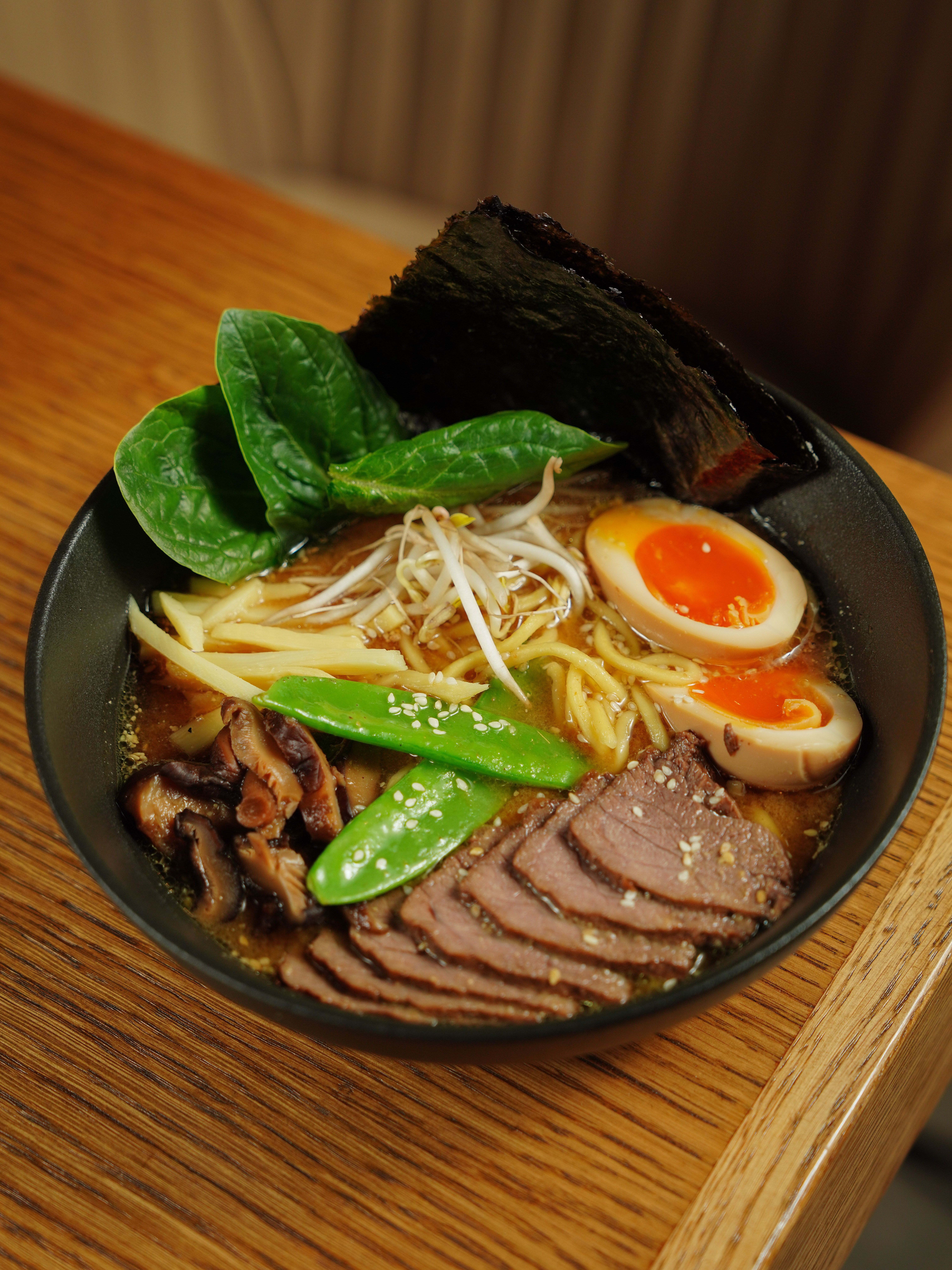 Close-up of a bowl of ramen with rich golden broth and noodles