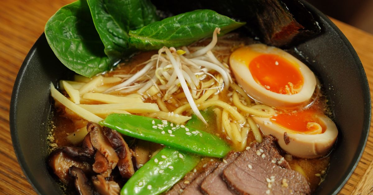 Rich golden ramen broth with noodles Close-up of a bowl of ramen with rich golden broth and noodles