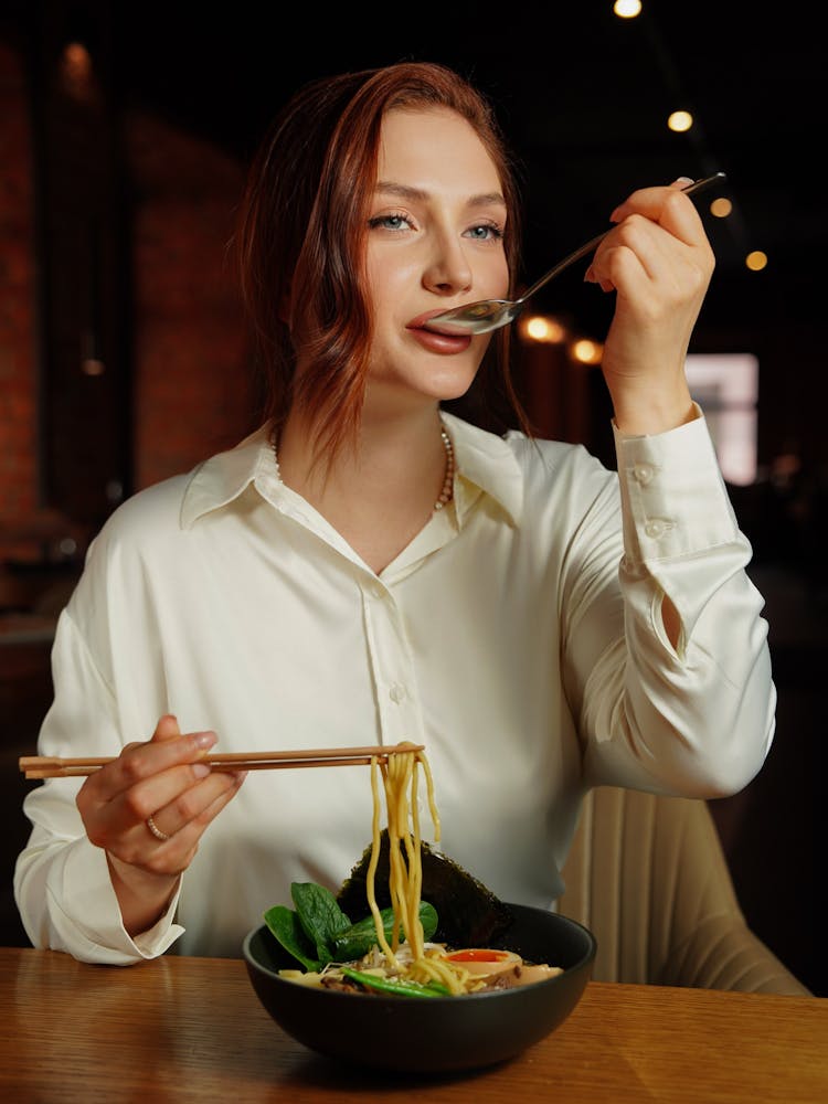 Woman Eating Delicious Ramen At Restaurant