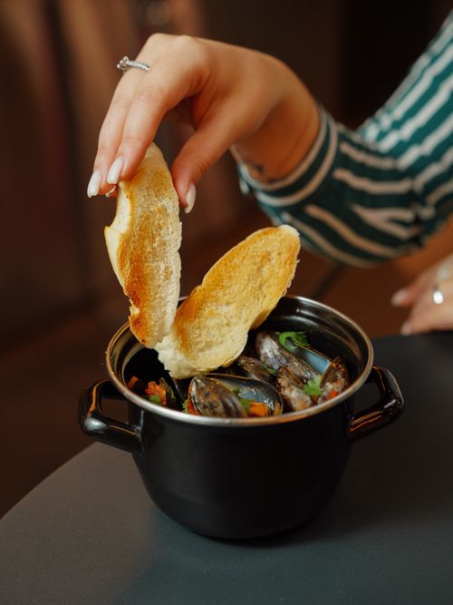 Free A savory seafood dish in black pot garnished with toasted bread slices, captured indoors. Stock Photo