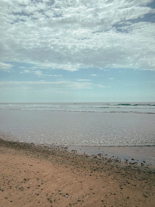 Free Serene beach view with gentle waves, cloudy sky, perfect for relaxation and travel inspiration. Stock Photo
