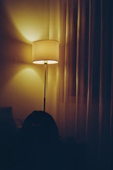 A warm and calming indoor scene featuring a glowing lamp beside gentle curtains.