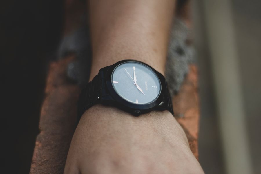 A dark-dialled dress watch on a wrist, photo by Pragyan Bezbaruah on Pexels