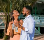 Smiling couple enjoying a cool drink on a sunny beach day.