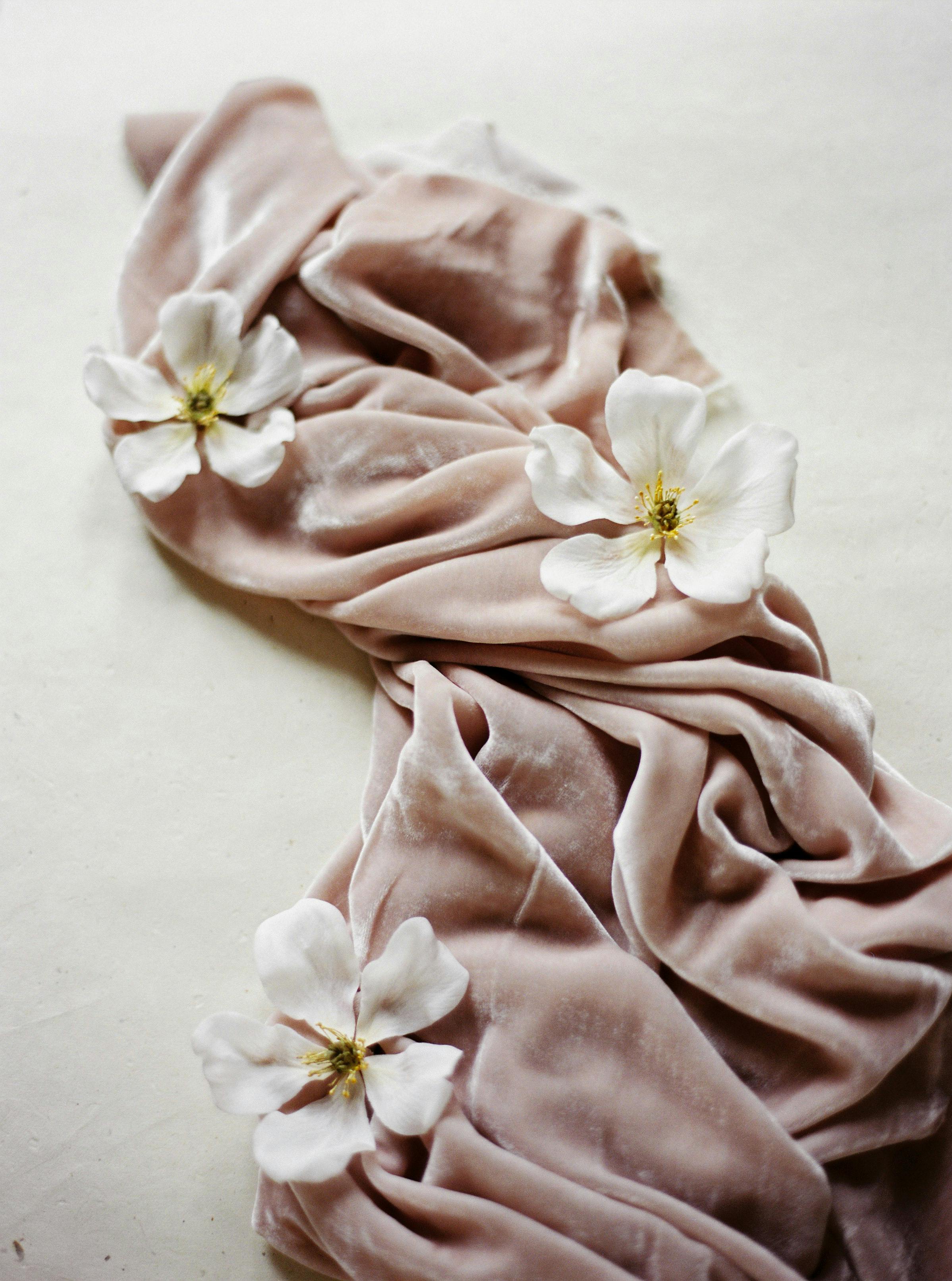 Soft pink velvet draped with delicate white flowers, creating a serene aesthetic.