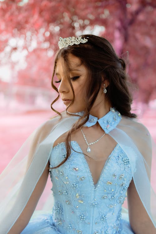 Young Woman in a Princess Dress and a Tiara Posing Outdoors 