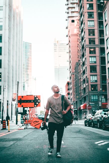 A young man strolls through the streets of downtown Toronto, surrounded by skyscrapers.