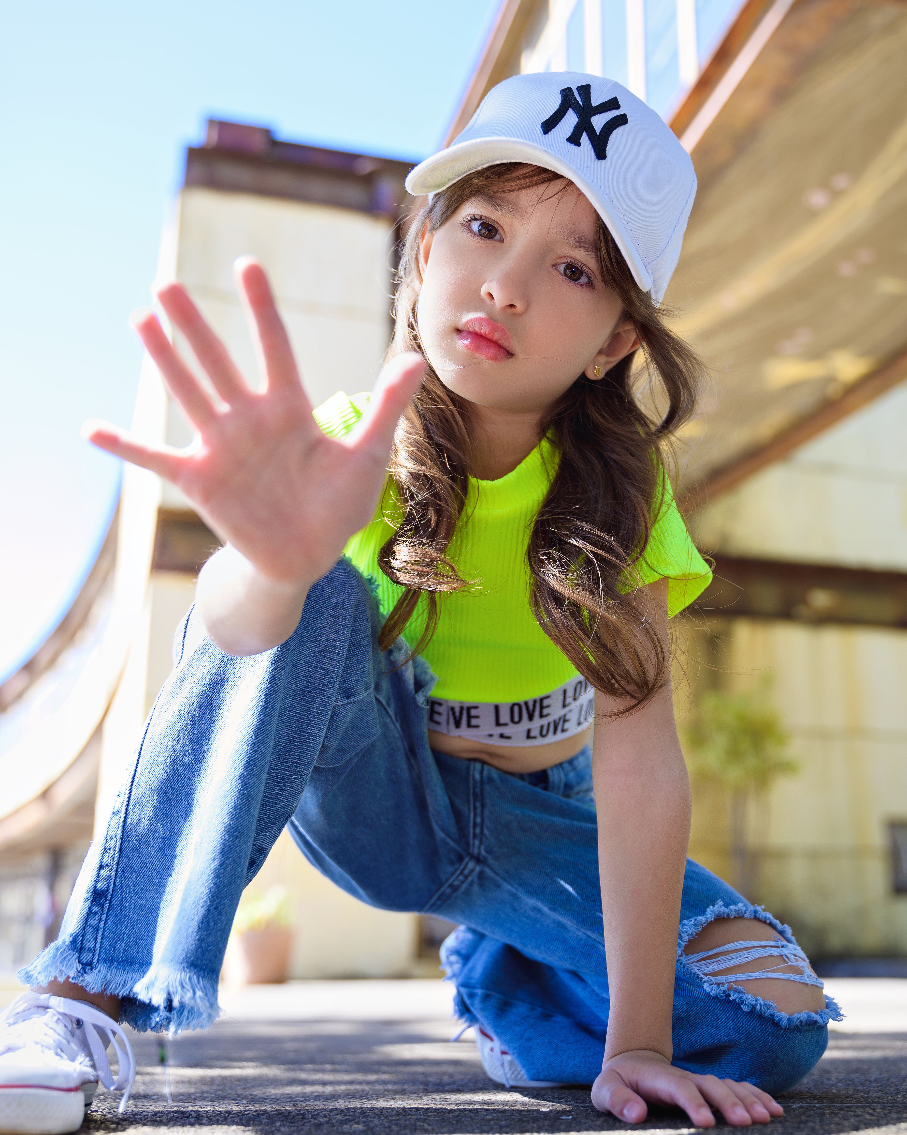 Stylish young girl in vibrant outfit posing confidently in an urban environment.