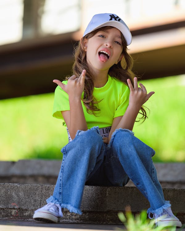 Young lady or teen girl in jeans and yellow t-shirt has fun taking funny  poses with her hands and leg up Stock Photo