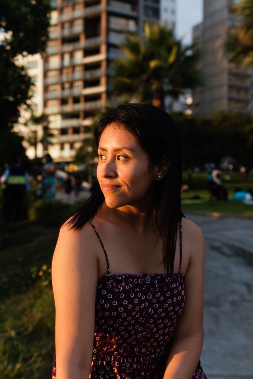 Free Young woman in sundress enjoying golden hour in Lima, Peru, with urban backdrop. Stock Photo