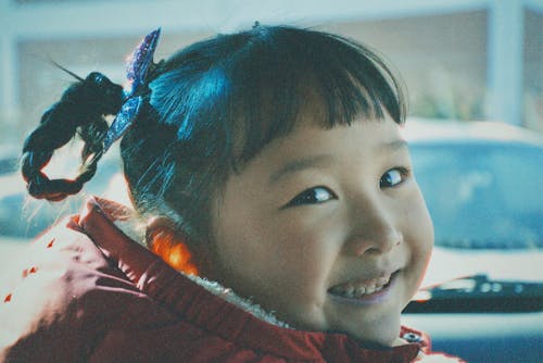 Film Photograph of a Little Girl with Bangs Looking over Her Shoulder and Smiling 