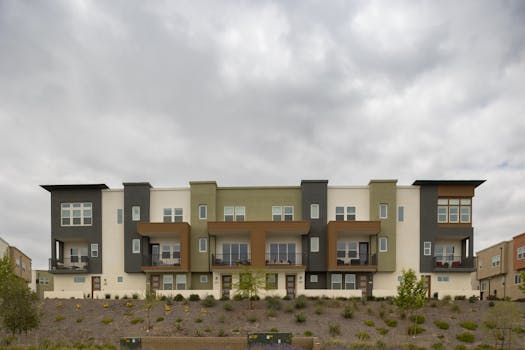 A contemporary apartment building with geometric design and overcast sky backdrop.