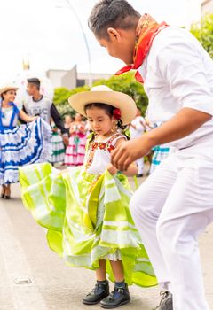 Colorful celebration of Mexican culture with people in traditional clothing dancing in a street parade.